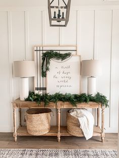 a wooden table topped with two baskets filled with greenery next to a white wall