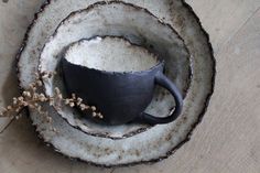 a black cup sitting on top of a white plate