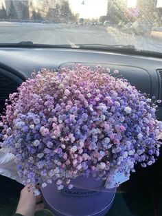 a purple bucket filled with lots of flowers sitting in the front seat of a car