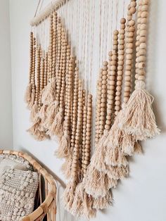 a wall hanging made out of wooden beads and tassels on a white wall