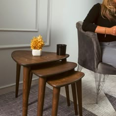 a woman sitting in a chair next to a table with three stools on it