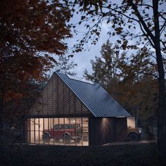 a small house in the woods at night with its lights on and two cars parked outside