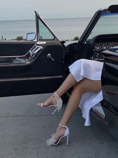 a woman sitting in the back of a black car with her feet on the door handle