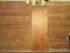 an empty room with wood paneling and a wooden door