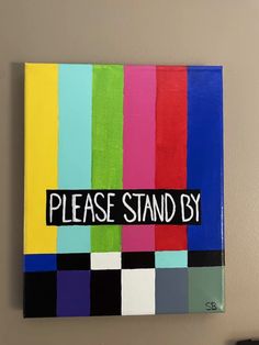 there is a sign that says please stand by on the side of a wall with different colors