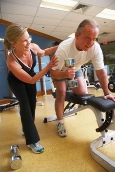 an older man and woman doing exercises in the gym