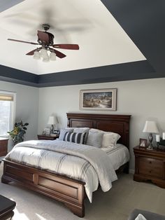 a bed room with a neatly made bed and a ceiling fan