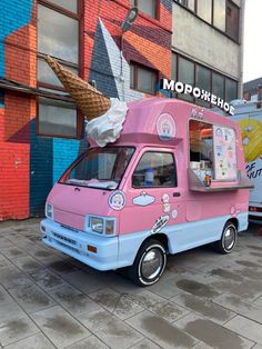 a pink ice cream truck parked in front of a building