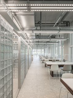 an empty room with tables and chairs in front of glass partitions on the wall