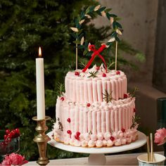 a pink cake sitting on top of a table next to a candle and some flowers