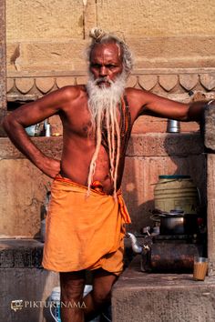 an old man with long white hair and beard standing in front of a stone building