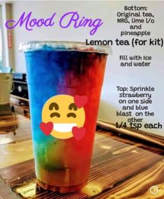 a colorful drink sitting on top of a wooden table next to a sign that says mood ring