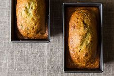 two loafs of bread sitting in pans on top of a table