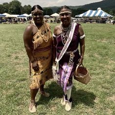 two women standing next to each other on a field with tents in the back ground