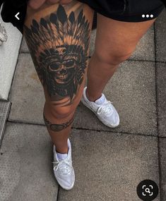 a person with tattoos on their legs standing next to a sidewalk and looking down at the ground