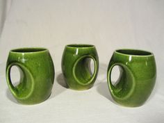 three green mugs sitting next to each other on a white tableclothed surface