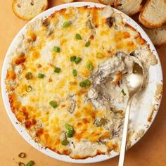 a white plate topped with food next to slices of bread and a spoon on top of it