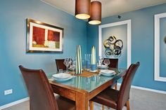 a dinning room with blue walls and brown leather chairs, an art piece on the wall