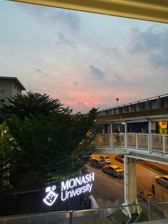 the sign for monash university is lit up at dusk in front of a parking lot