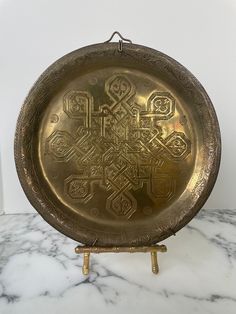 an antique brass plate with intricate designs on the front and sides sitting on a marble table