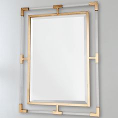 a square mirror with gold trim around the edges and a white rectangular frame on top