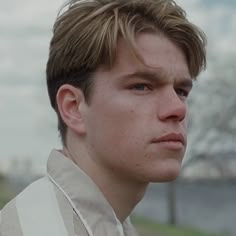 a close up of a person wearing a white shirt and looking off to the side