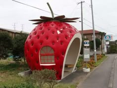 a large strawberry shaped building sitting on the side of a road