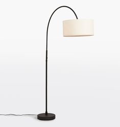 a black floor lamp with a white shade on the base and a round light fixture