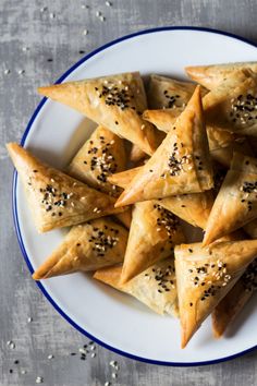 a white plate topped with pastries covered in sesame seeds