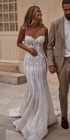 a man and woman are walking down the street holding hands while dressed in wedding attire