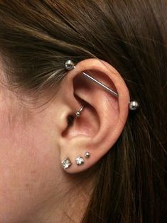 a woman's ear has three piercings on it