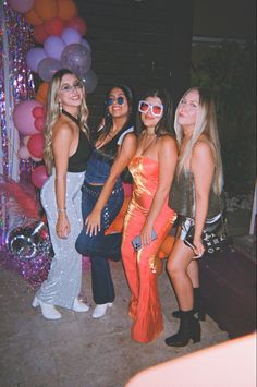 four women posing for the camera with balloons in the background