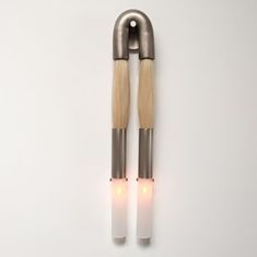 two silver and wood handles with white lights on them are attached to the wall in front of a white background