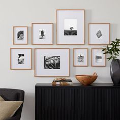 there are many pictures on the wall with frames above it and a vase next to them