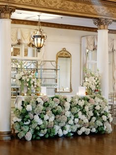 a table with flowers and candles on it in a large room next to a chandelier