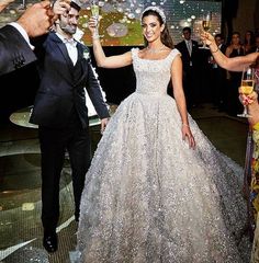 a man and woman holding champagne flutes in front of a group of people wearing tuxedos