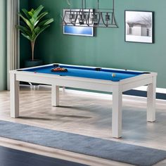 a pool table in a living room with blue and white walls, rugs and pictures on the wall