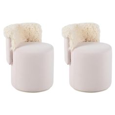 two white chairs with sheepskin on them sitting side by side in front of each other