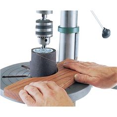 a person working on a piece of wood with a machine in front of him and an object behind it