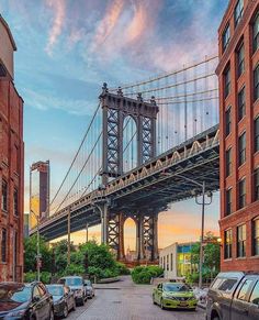 cars parked on the side of a road under a bridge in new york city at sunset