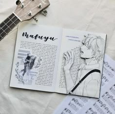 an open book sitting on top of a table next to music sheets and guitar strings