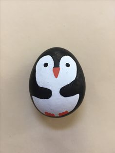 a painted rock with a black and white penguin on it's face is shown