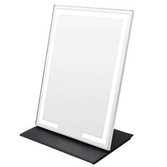 a white framed mirror sitting on top of a black stand with an electronic device in front of it