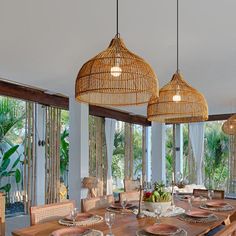 a dining room table with place settings and hanging lights