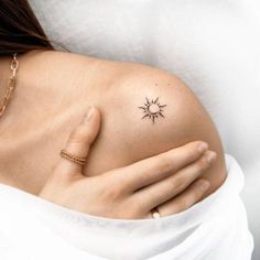 a woman's shoulder with a small sun tattoo on the left side of her arm