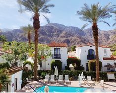 an outdoor swimming pool with palm trees and mountains in the backgrouds behind it