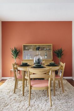 a dining room with orange walls and white rugs on top of the carpeted floor