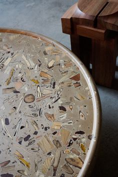 a wooden bench sitting next to a round table with glass on the top and bottom