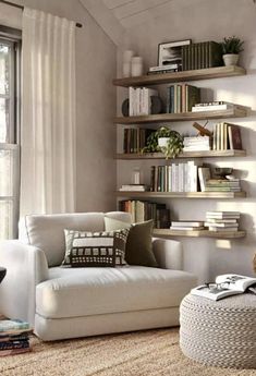 a living room filled with furniture and bookshelves next to a window covered in white curtains