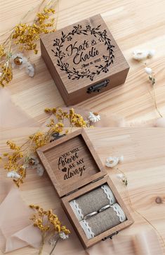 two wooden boxes with wedding rings inside sitting on top of a table next to flowers